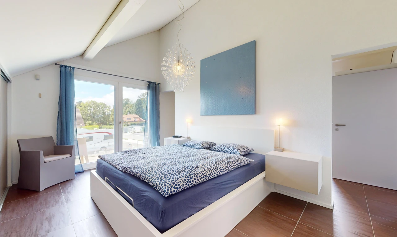 chambre avec plancher de bois, lumière naturelle, plafond voûté, et poutres apparentes