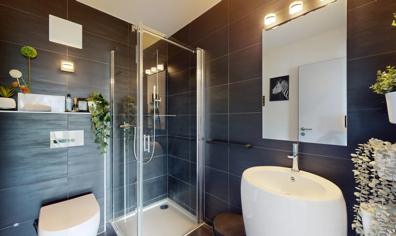 salle de bains avec mur carrelé, toilettes, miroir, et douche