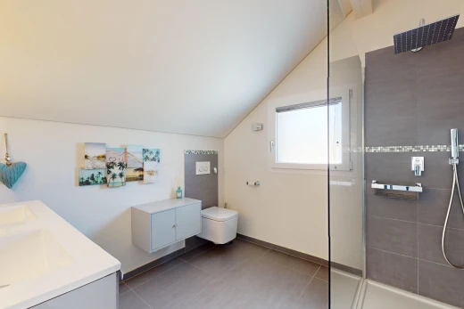 salle de bains avec toilettes, plafond voûté, meuble-lavabo, lumière naturelle, et douche