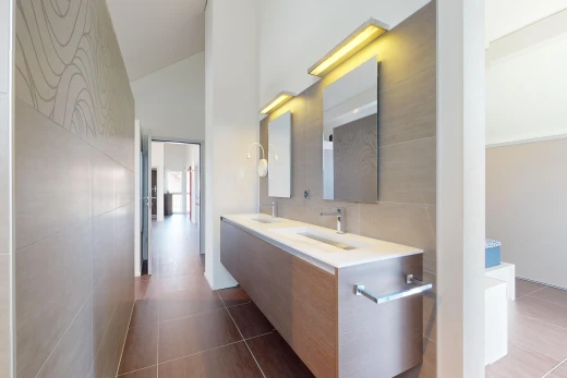salle de bains avec miroir, plafond voûté, haut plafond, meuble-lavabo, et mur carrelé