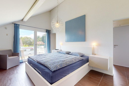 chambre avec plancher de bois, lumière naturelle, plafond voûté, et poutres apparentes