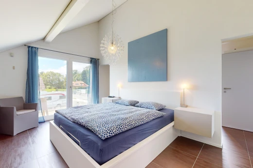 chambre avec plancher de bois, lumière naturelle, plafond voûté, et poutres apparentes