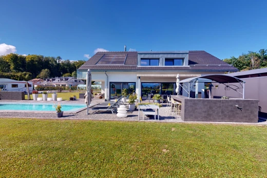 façade avec panneaux solaires, patio, piscine, et pelouse