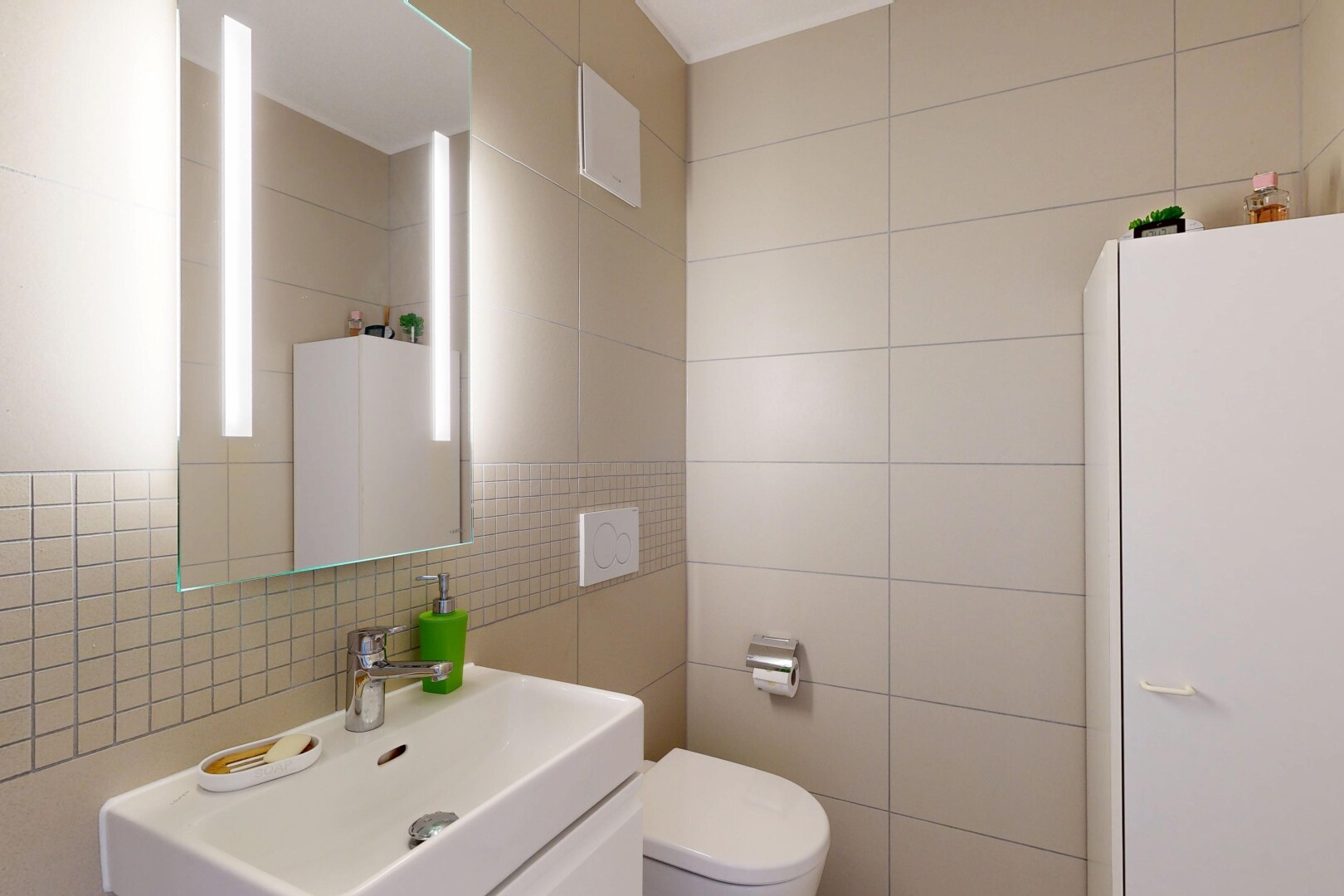 salle de bains avec mur en carrelage, tile wall, toilette, évier, et miroir