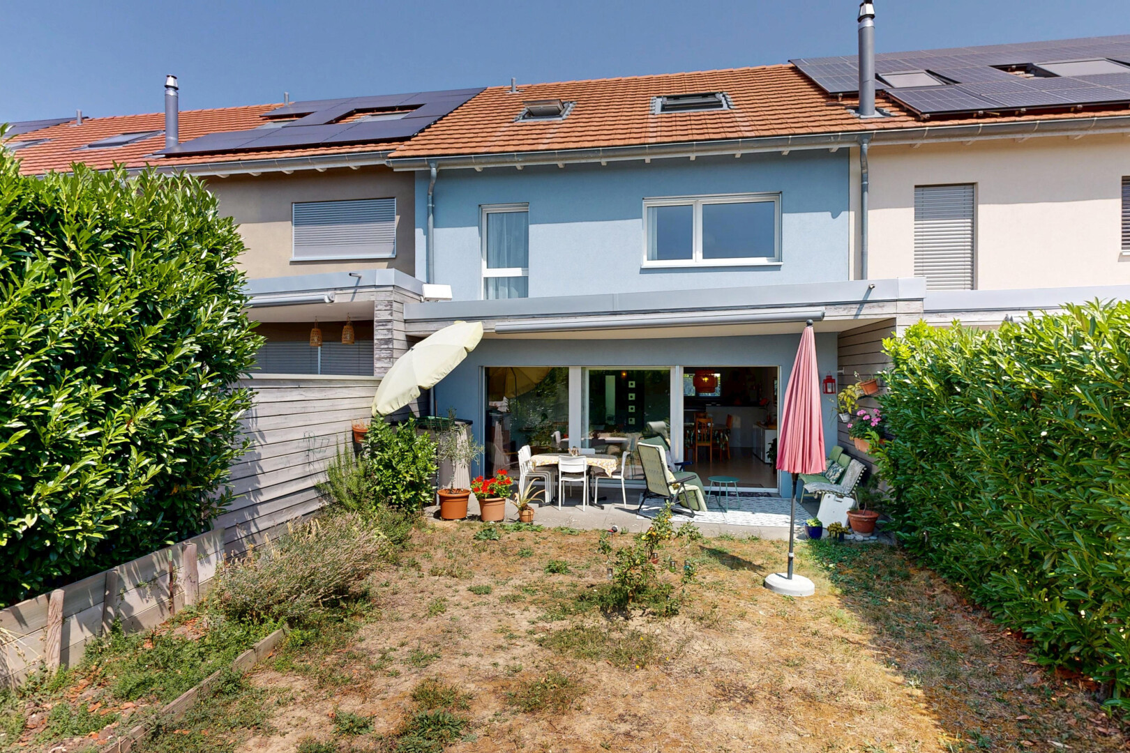 façade avec terrasse, property visible, panneaux solaires, bardage en stuc, et day time