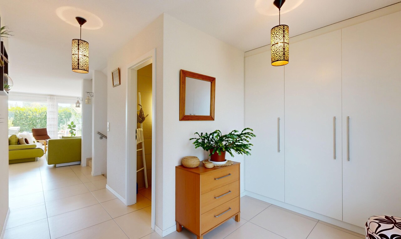 couloir avec éclairage suspendu, drywall, cloison sèche, light floor, et tile floor