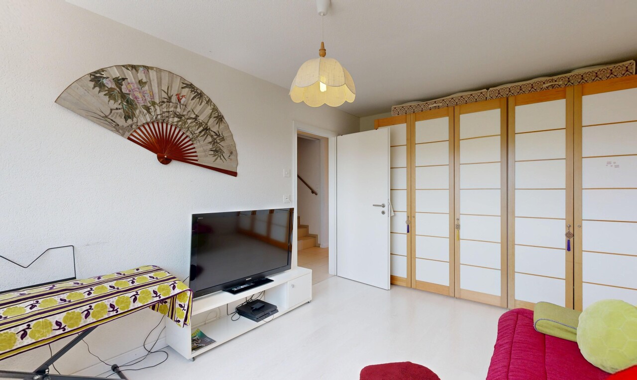 salon avec télévision, escaliers, cloison sèche, drywall, et éclairage suspendu