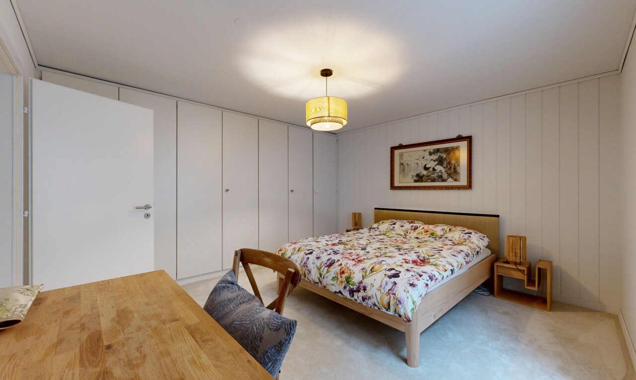 room with a desk, pendant lighting, light carpet, wood walls, and a closet