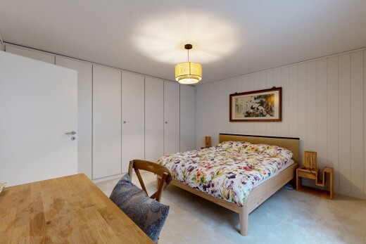 room with a desk, pendant lighting, light carpet, wood walls, and a closet