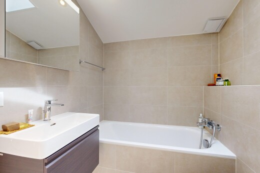 bathroom with vanity, tile walls, and a bath