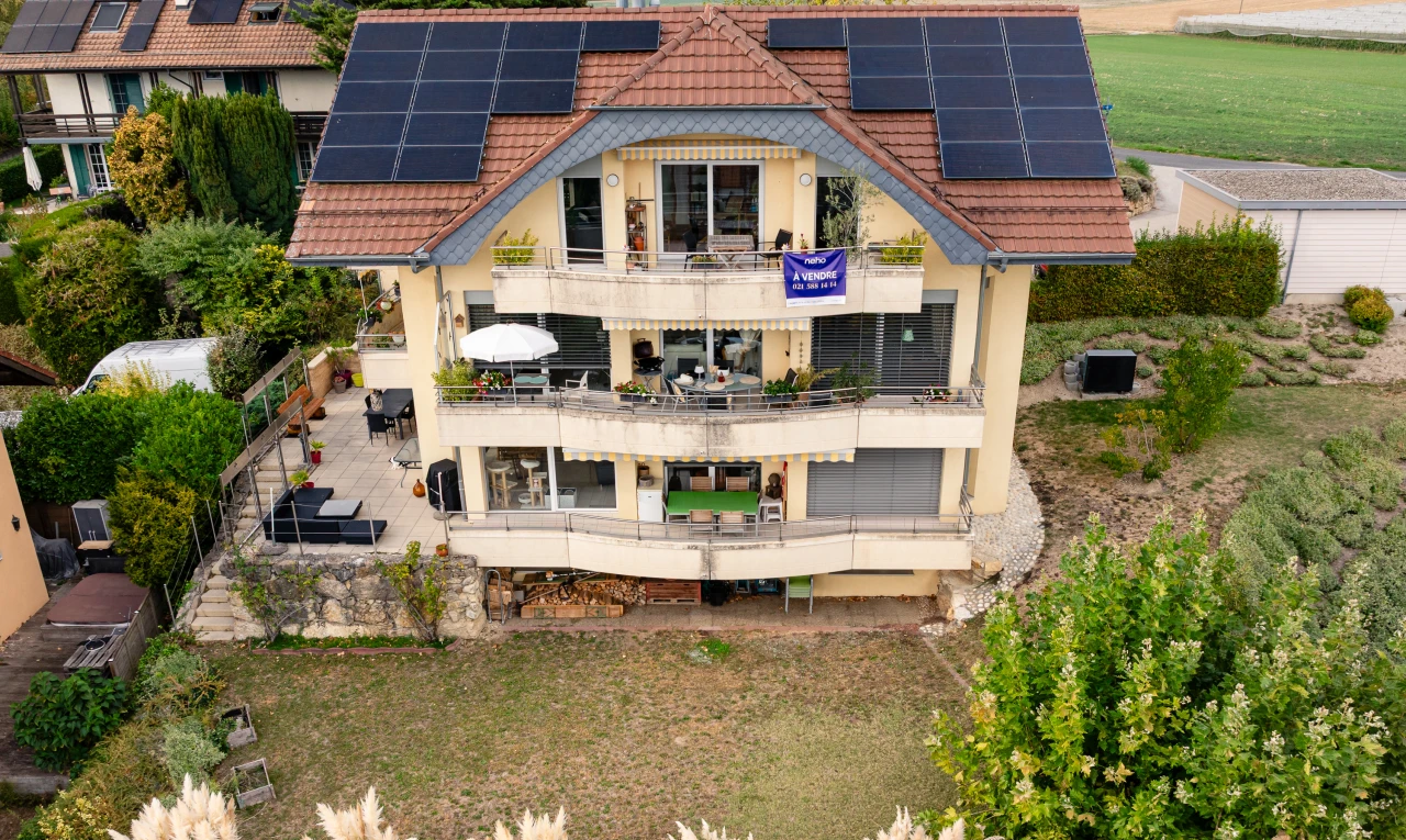 façade avec panneaux solaires, coin repas extérieur, toit en tuiles, property visible, et drone view