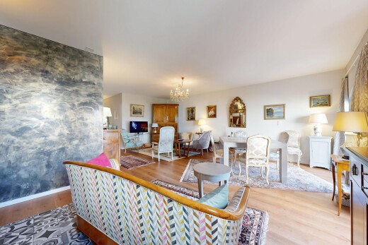 salon avec lustre remarquable, wood finish floor, sol en finition bois, inside property, et télévision