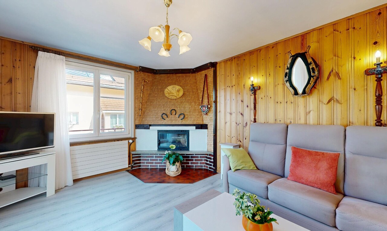 salon avec télévision, dated wood wall, cheminée, wood finish floor, et sol en finition bois
