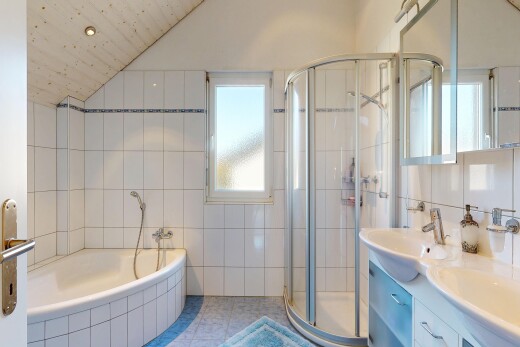 bathroom with double vanity, a garden tub, tile walls, a stall shower, and lofted ceiling