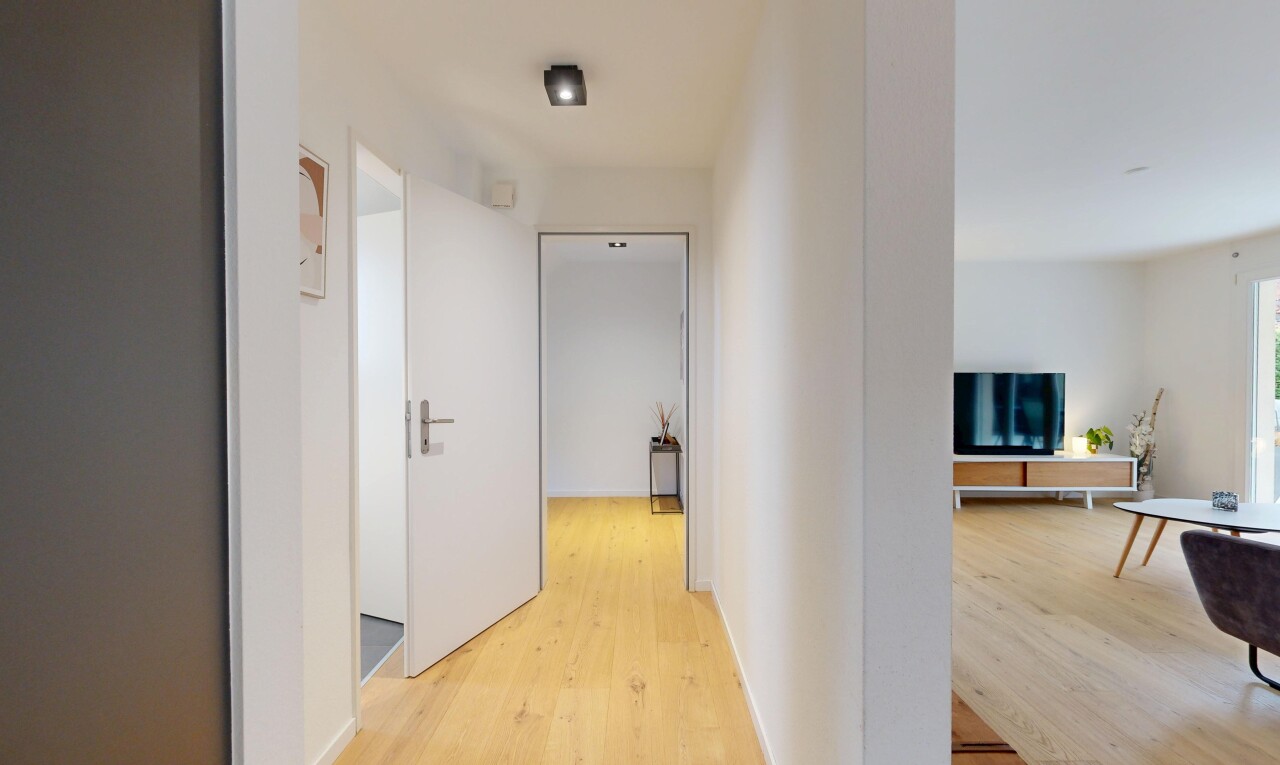 halle / korridor mit inside property, fernseher, wood finish floor, holzfußboden, und drywall