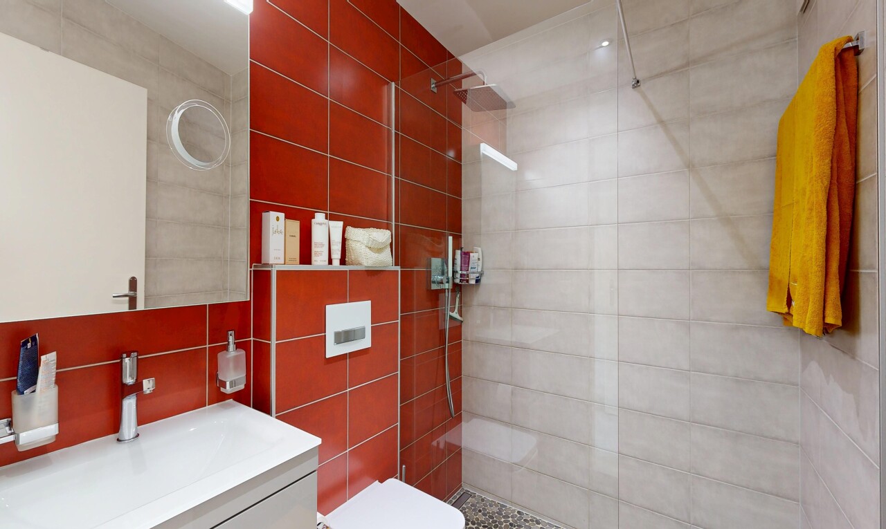 salle de bains avec lavabo (ou coiffeuse selon le contexte), douche, miroir, salle de bain complète, et tile wall