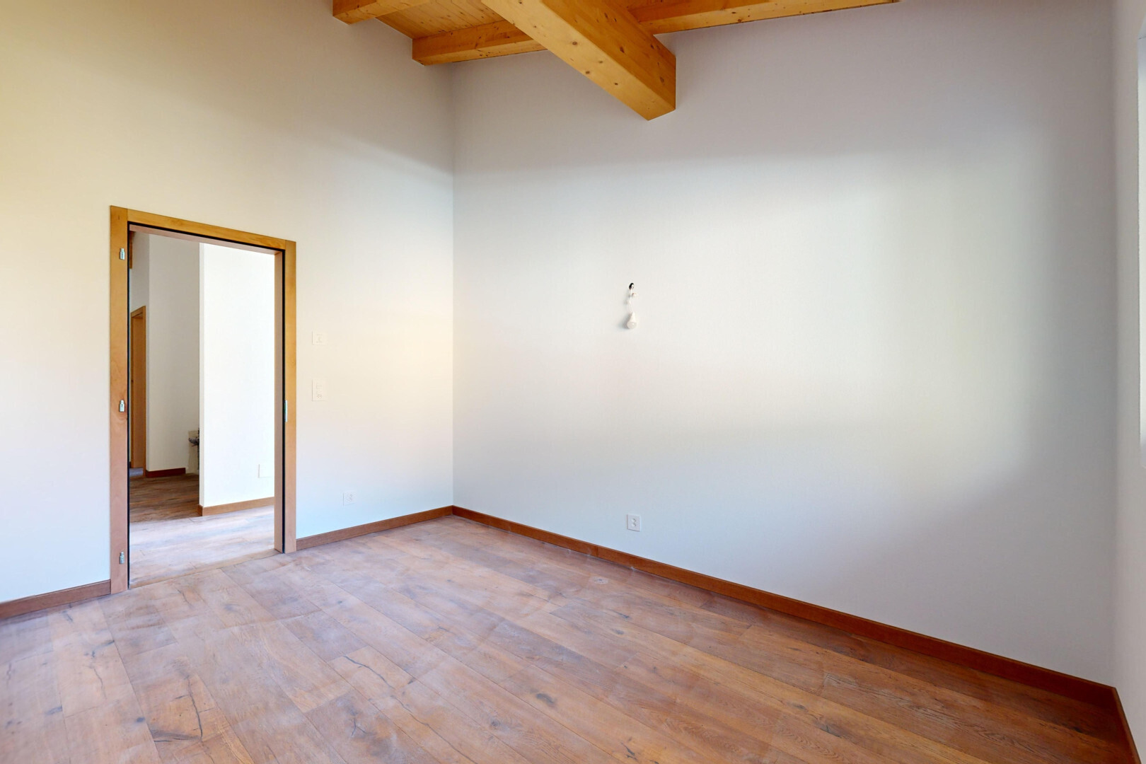pièce vide avec sol en finition bois, wood finish floor, plafond à poutres, beamed ceiling, et cloison sèche