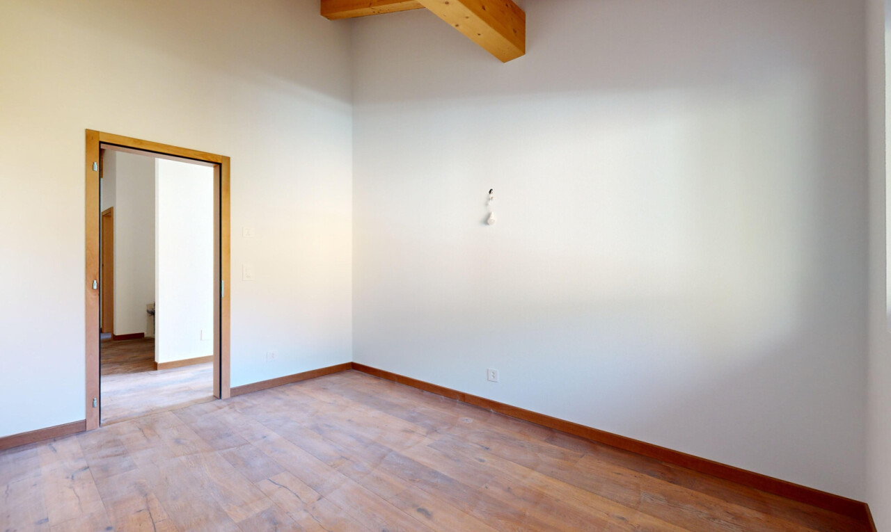 pièce vide avec sol en finition bois, wood finish floor, plafond à poutres, beamed ceiling, et cloison sèche