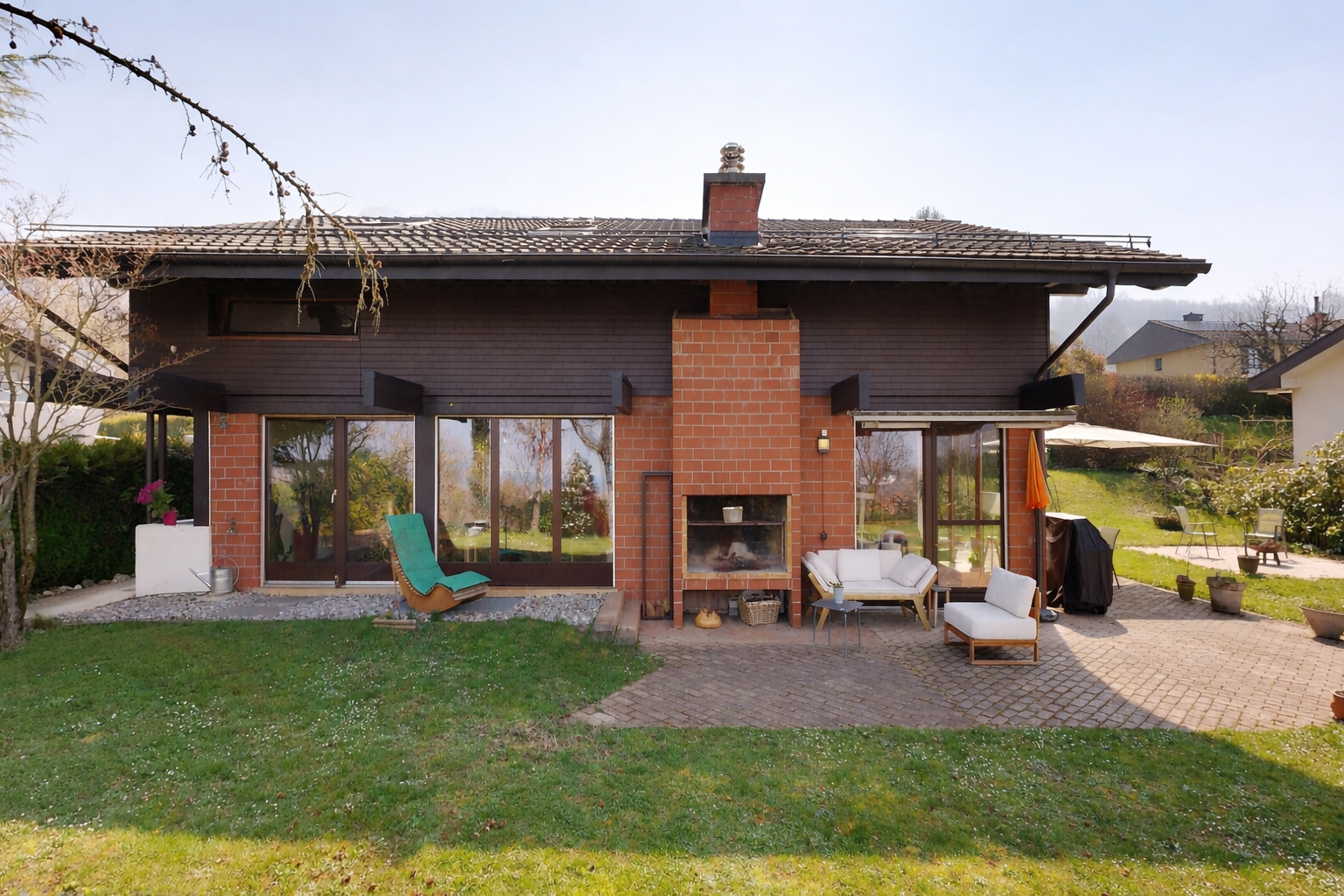 façade avec cheminée, terrasse, pelouse, property visible, et bardage horizontal