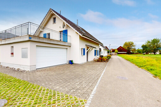 außenansicht mit rasen, auffahrt, property visible, garage, und stuckverkleidung