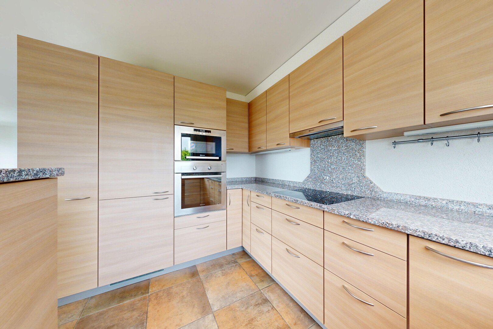 cuisine avec armoires marron clair, light brown cabinets, plans de travail en pierre, stone countertops, et four