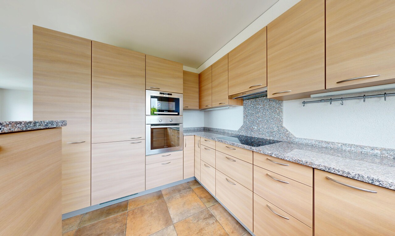 cuisine avec armoires marron clair, light brown cabinets, plans de travail en pierre, stone countertops, et four