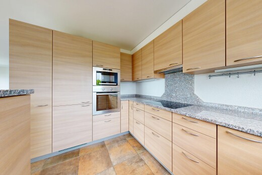 cuisine avec armoires marron clair, light brown cabinets, plans de travail en pierre, stone countertops, et four