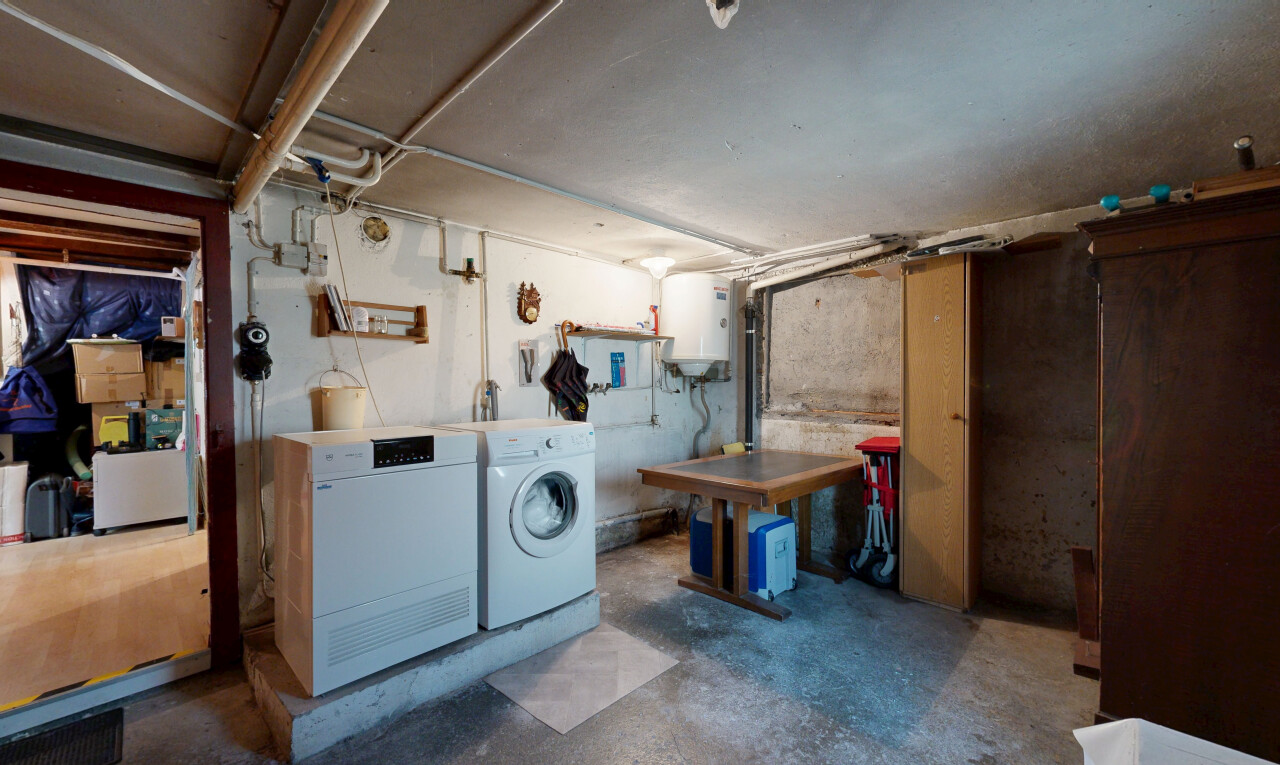buanderie avec concrete floor, sol en béton, sous-sol, inside property, et chauffe-eau