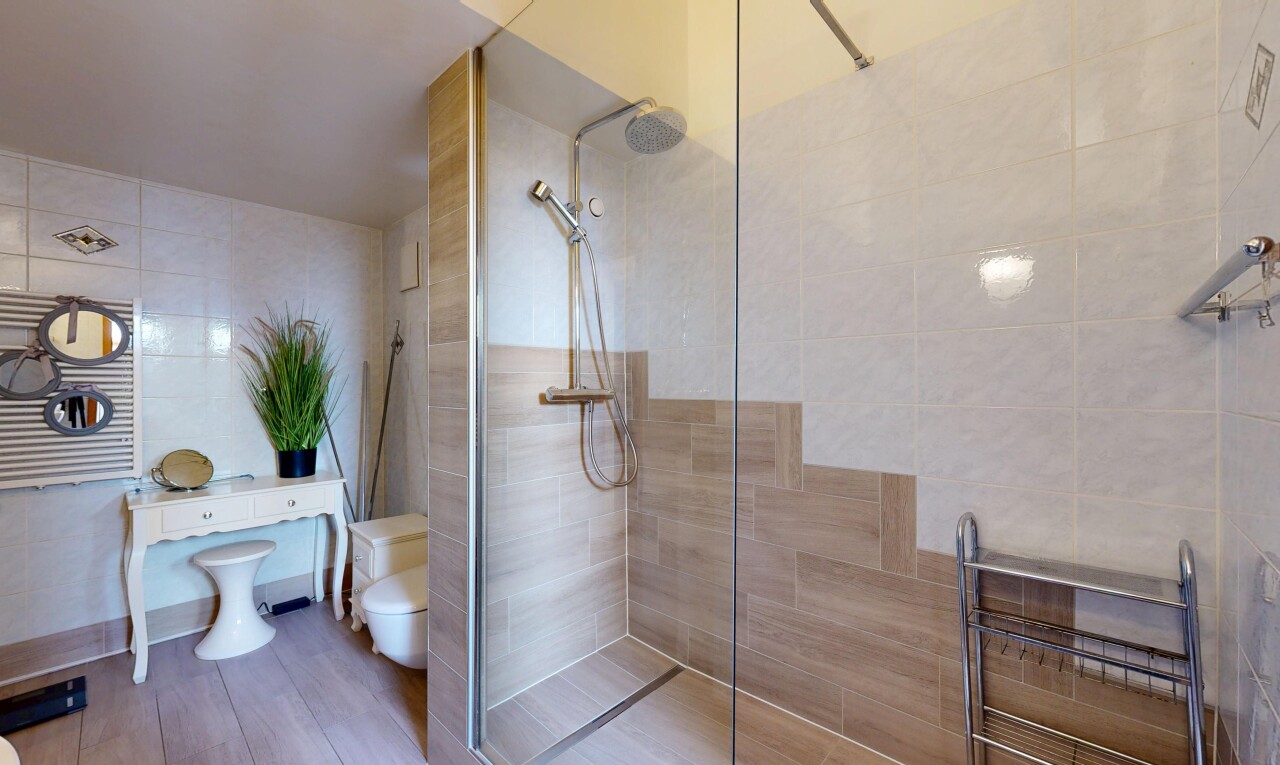 salle de bains avec salle de bain complète, douche, chauffe-serviettes, inside property, et mur en carrelage