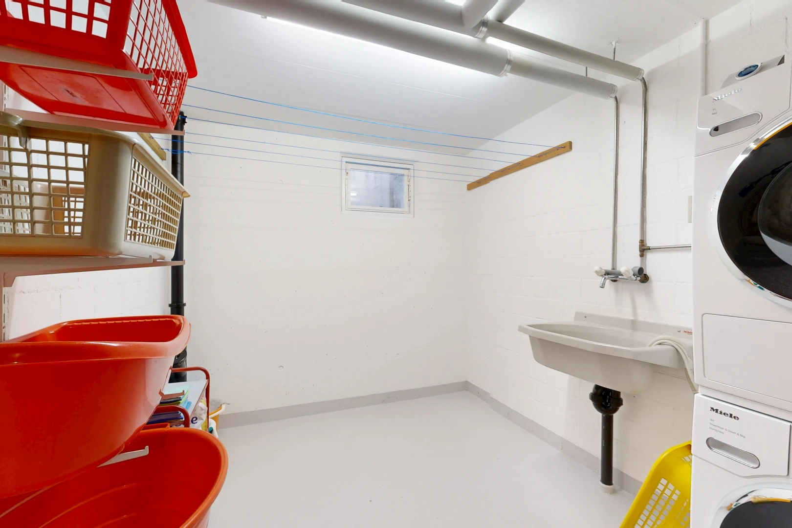 buanderie avec inside property, sol en béton, concrete floor, lave-linge et sèche-linge superposés, et finished concrete floor