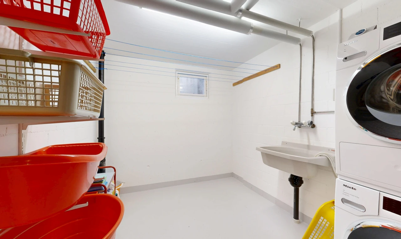 buanderie avec inside property, sol en béton, concrete floor, lave-linge et sèche-linge superposés, et finished concrete floor