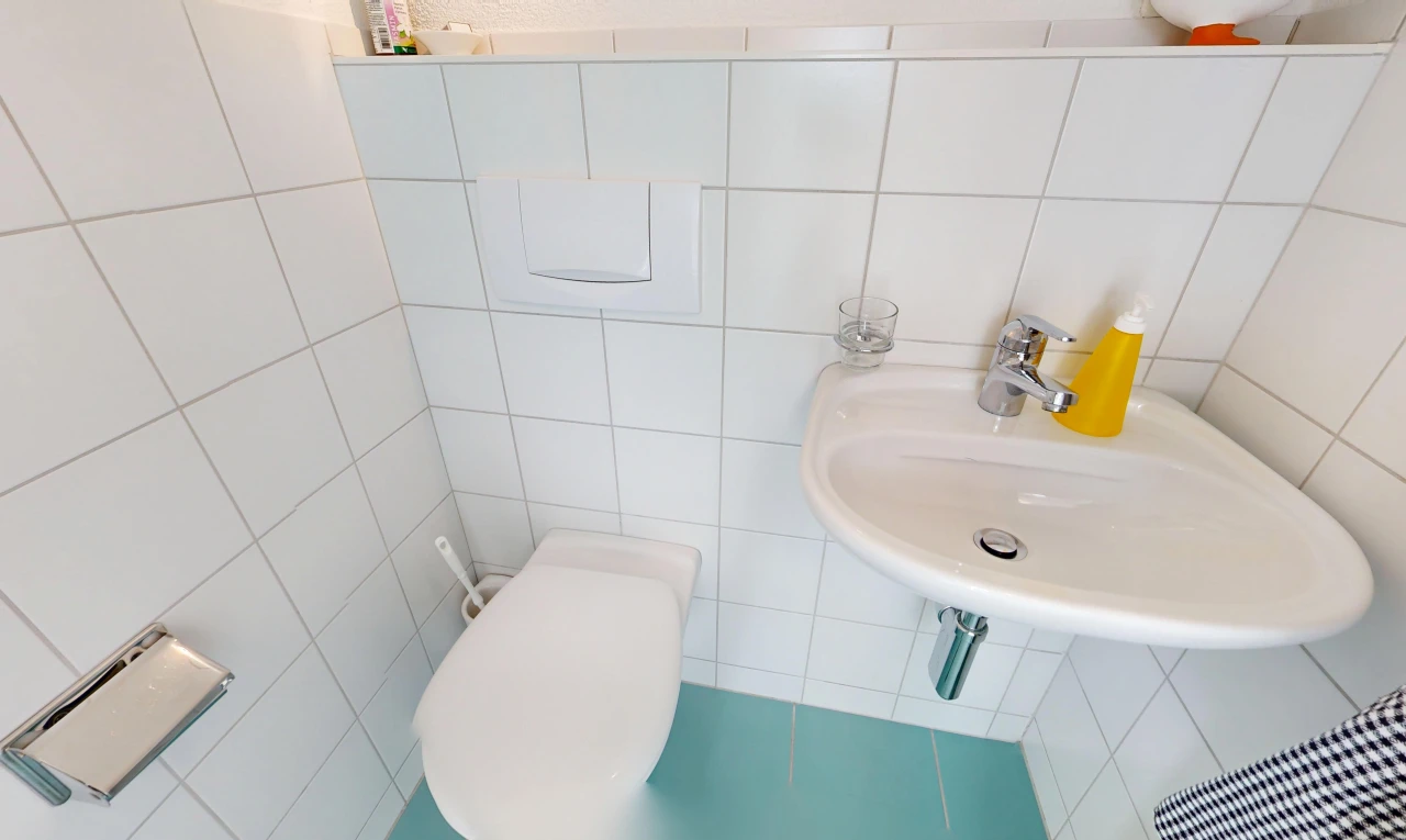 salle de bains avec évier, mur en carrelage, tile wall, et toilette