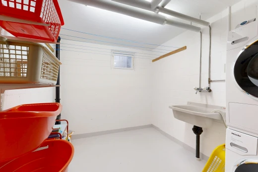 buanderie avec inside property, sol en béton, concrete floor, lave-linge et sèche-linge superposés, et finished concrete floor