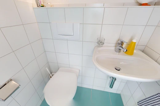 salle de bains avec évier, mur en carrelage, tile wall, et toilette