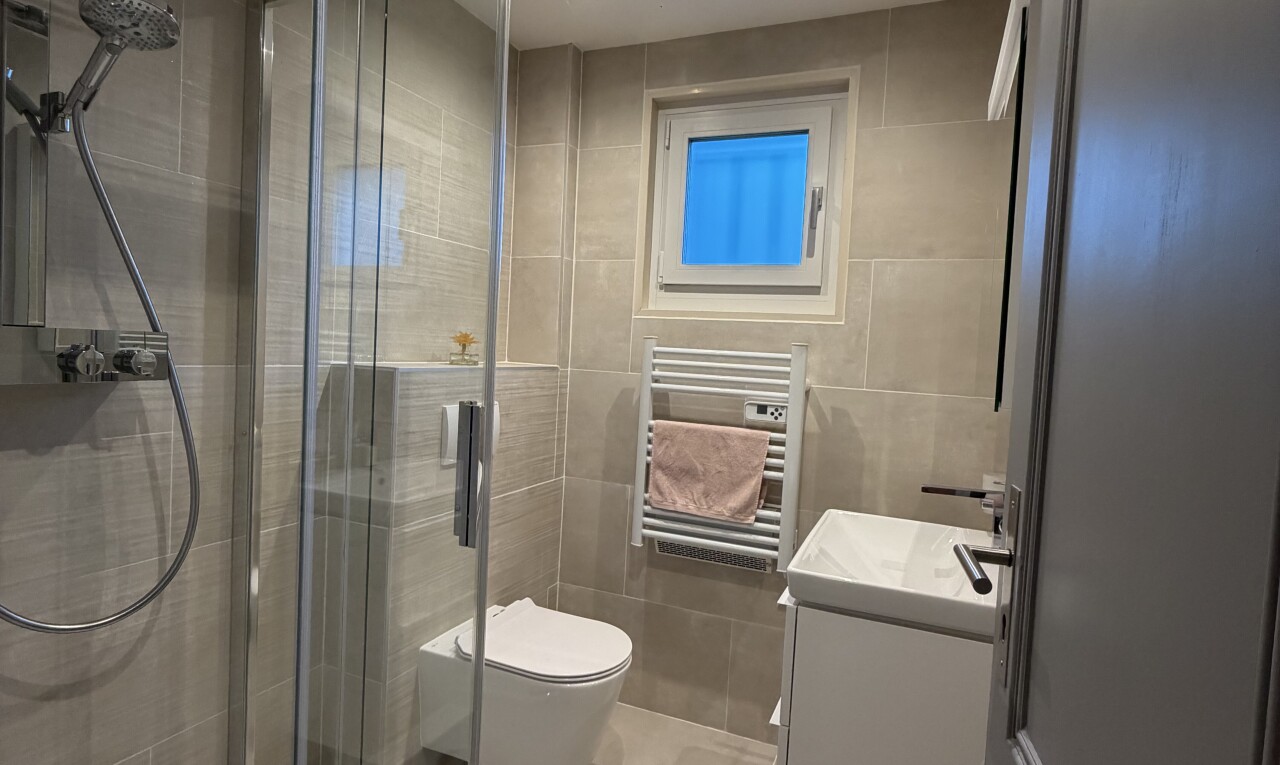 salle de bains avec chauffe-serviettes, tile wall, mur en carrelage, douche, et radiateur