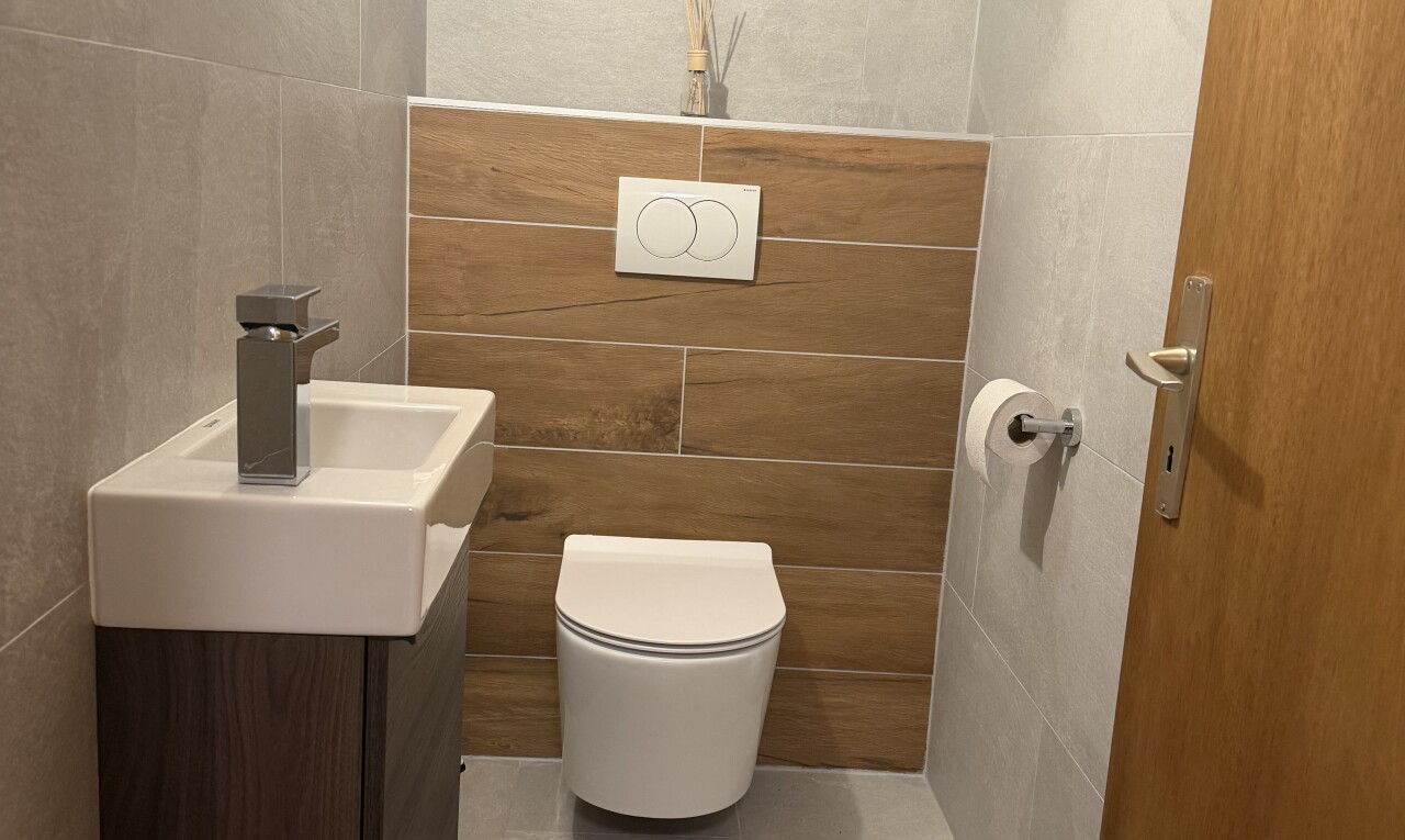 salle de bains avec tile wall, mur en carrelage, lavabo (ou coiffeuse selon le contexte), toilette, et inside property