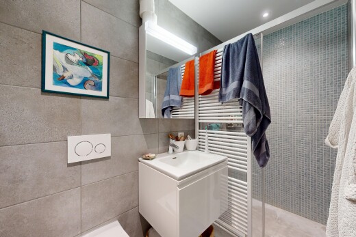 salle de bains avec chauffe-serviettes, douche, salle de bain complète, miroir, et lavabo (ou coiffeuse selon le contexte)