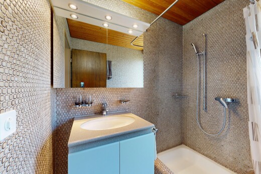 salle de bains avec douche, salle de bain complète, évier, lavabo (ou coiffeuse selon le contexte), et mur en carrelage