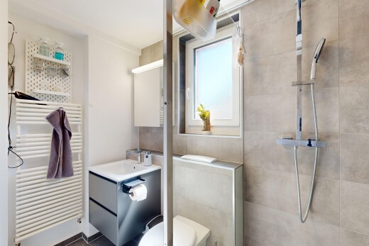 salle de bains avec radiateur, douche, lavabo (ou coiffeuse selon le contexte), chauffe-serviettes, et salle de bain complète