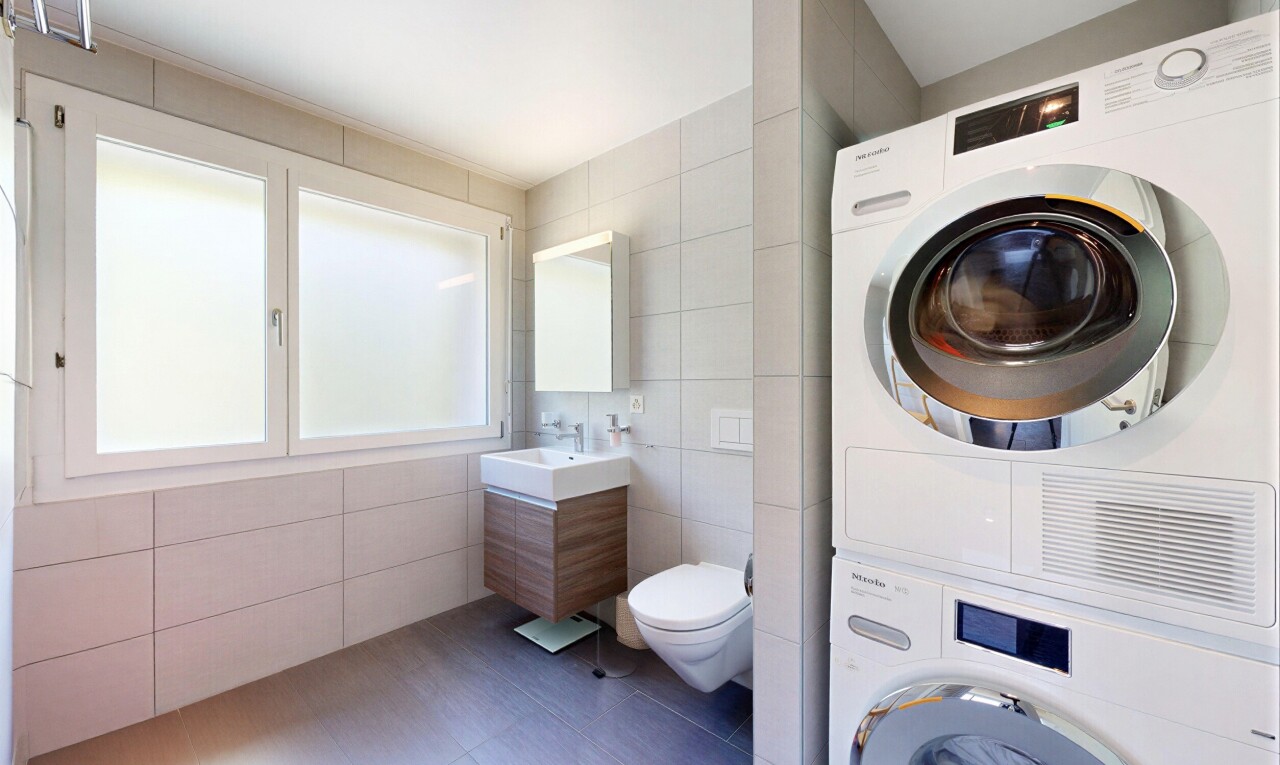 bathroom with tile walls, stacked washer / dryer, vanity, and tile patterned floors