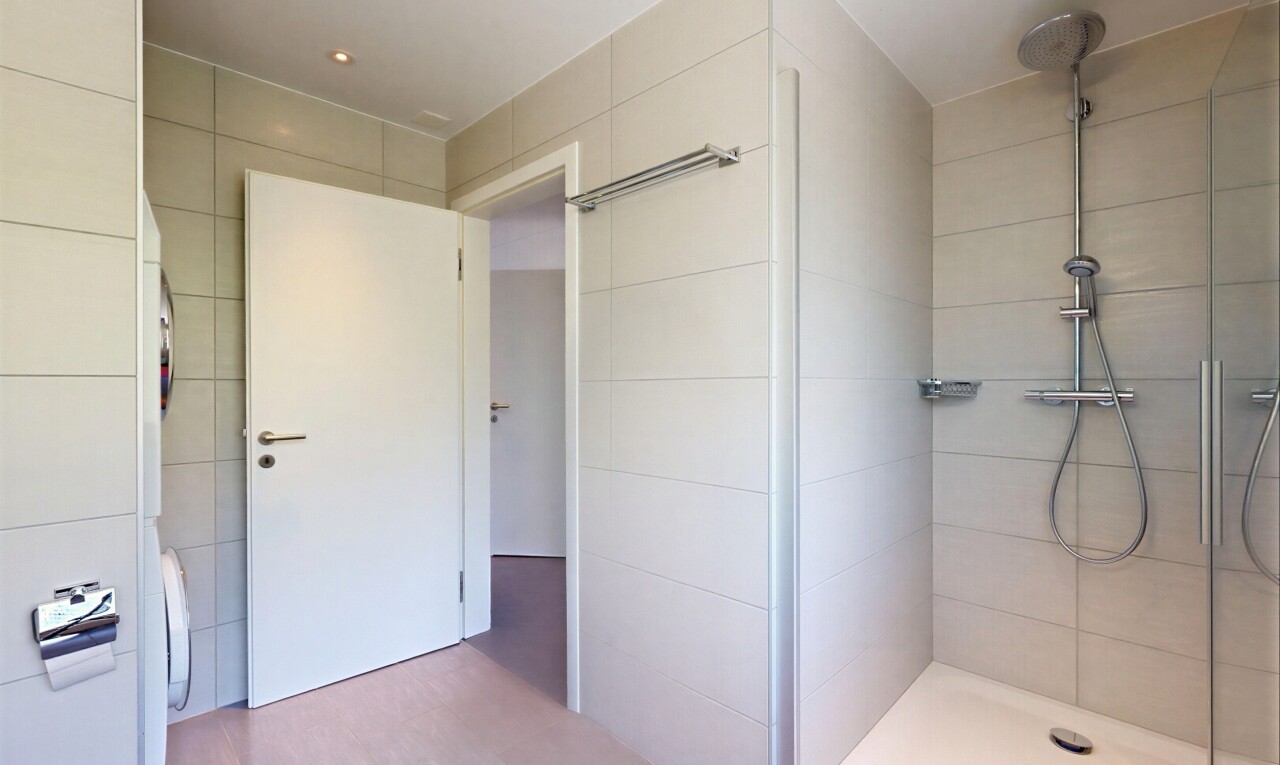 bathroom featuring a tile shower, tile walls, and washer / clothes dryer