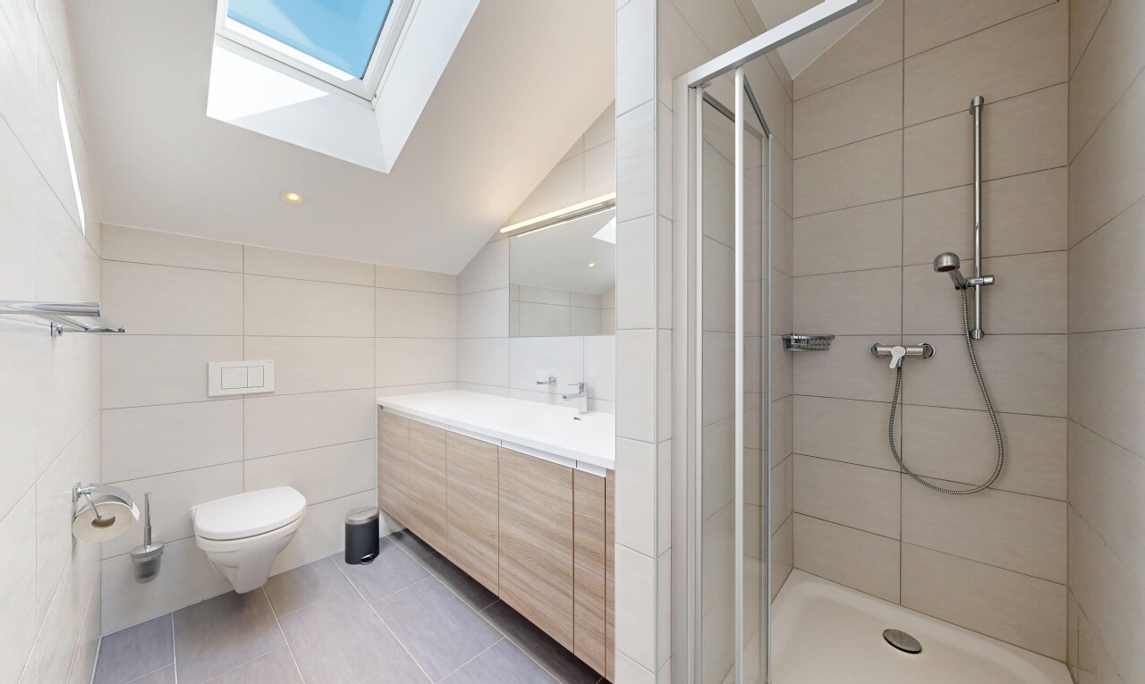 bathroom with tile walls, light tile patterned floors, a shower stall, vaulted ceiling, and vanity