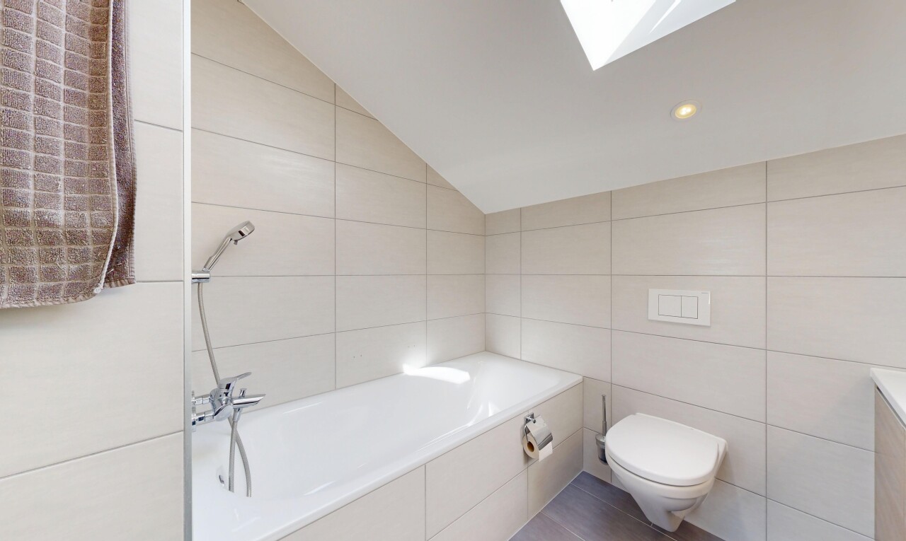 bathroom featuring tile walls, lofted ceiling, a garden tub, a skylight, and recessed lighting