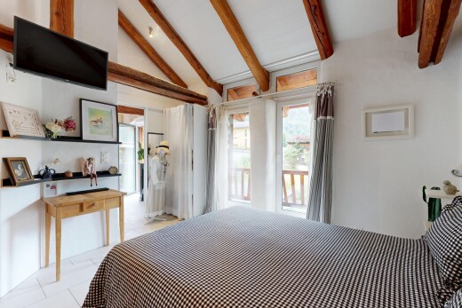 zimmer / schlafzimmer mit fernseher, beamed ceiling, balkendecke, vaulted ceiling, und dachschräge