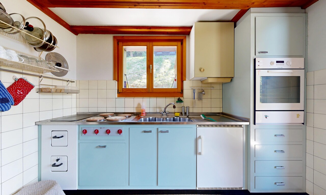 cuisine avec four, dark floor, évier, inside property, et drywall