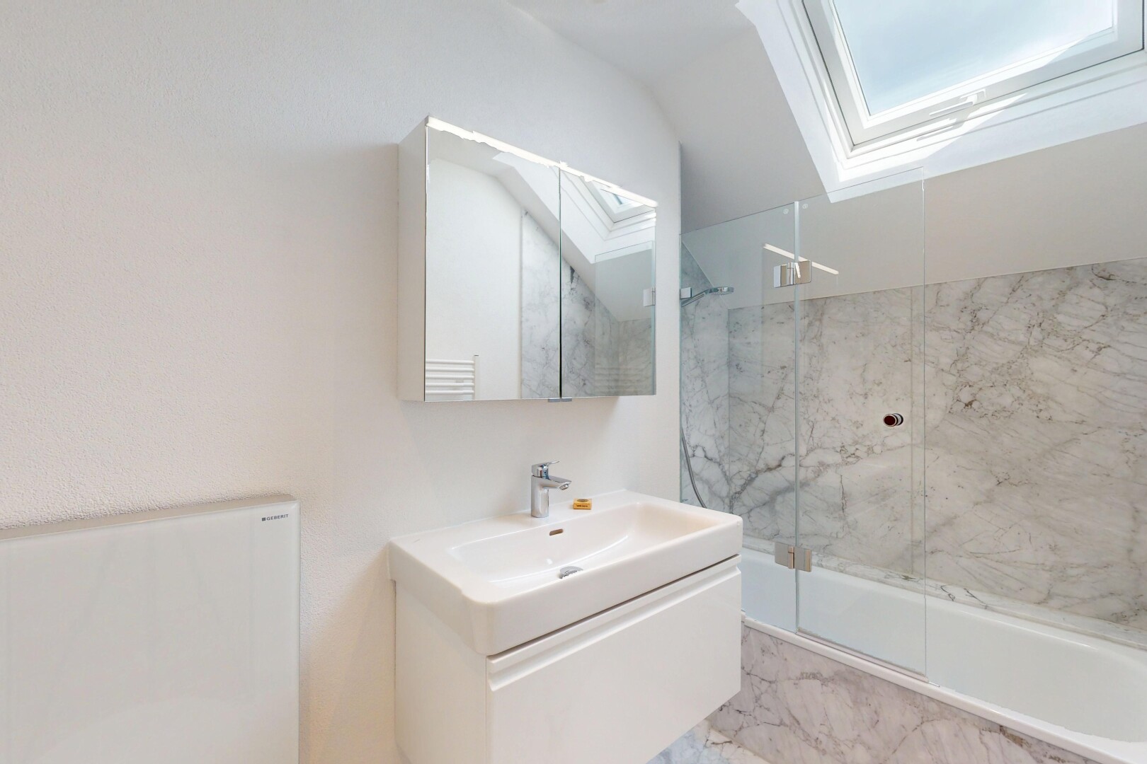 salle de bains avec puits de lumière, lavabo (ou coiffeuse selon le contexte), douche, bain, et miroir