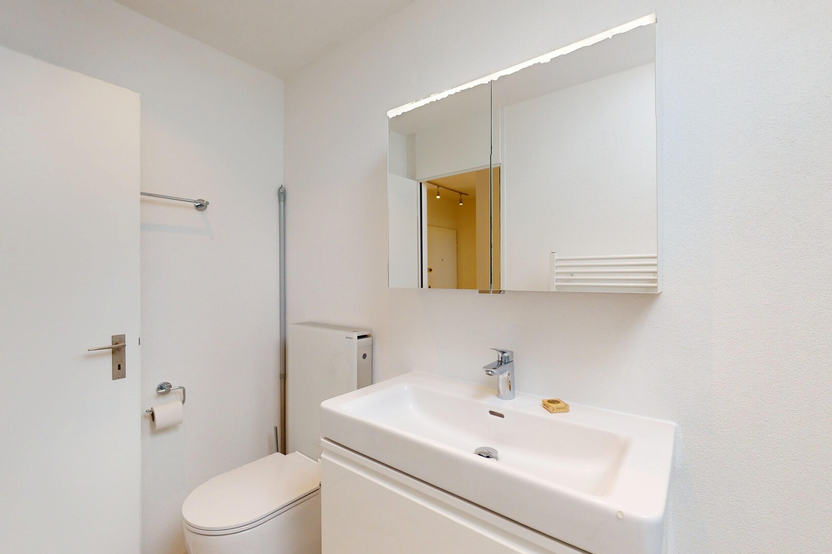 salle de bains avec évier, toilette, cloison sèche, lavabo (ou coiffeuse selon le contexte), et miroir