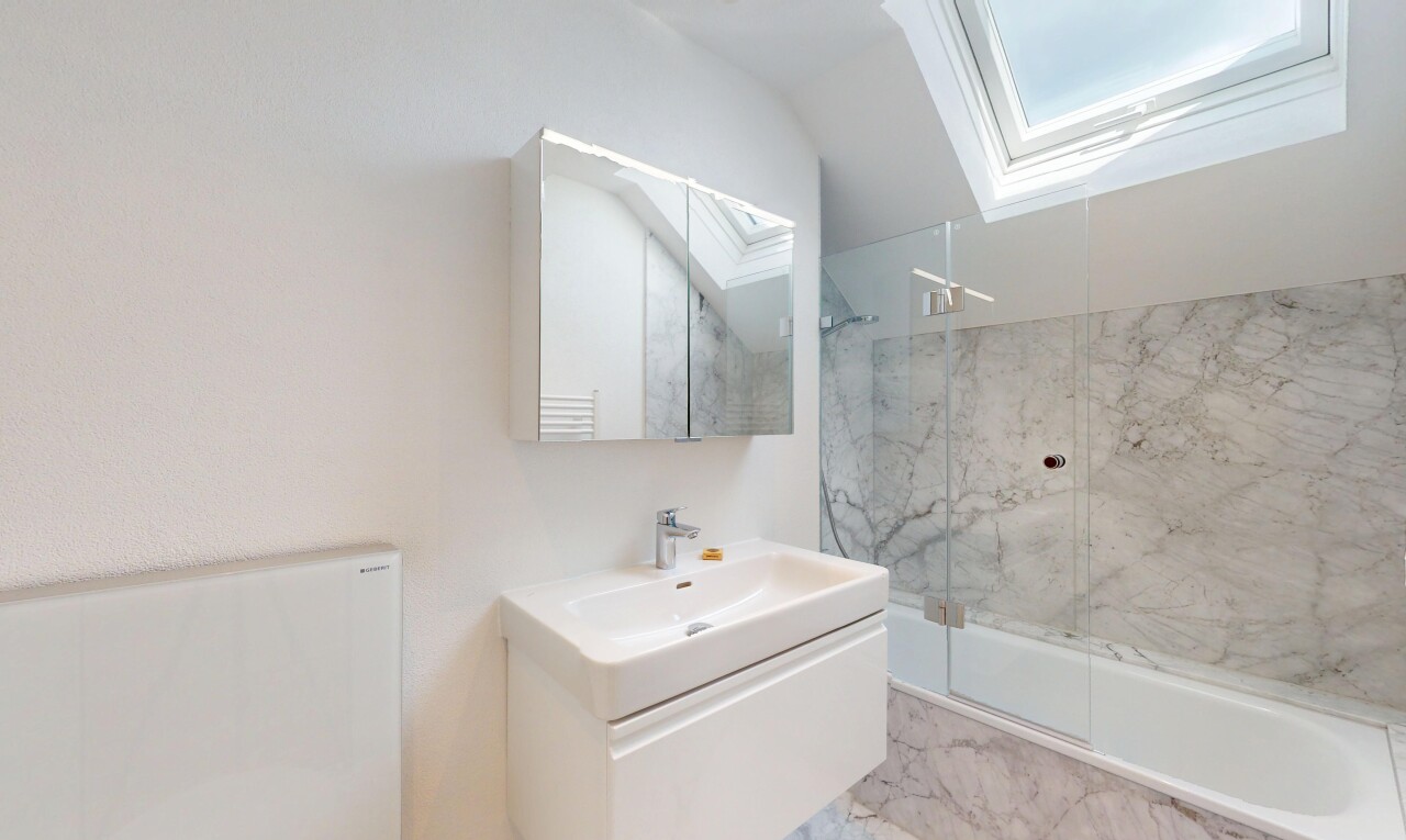 salle de bains avec puits de lumière, lavabo (ou coiffeuse selon le contexte), douche, bain, et miroir