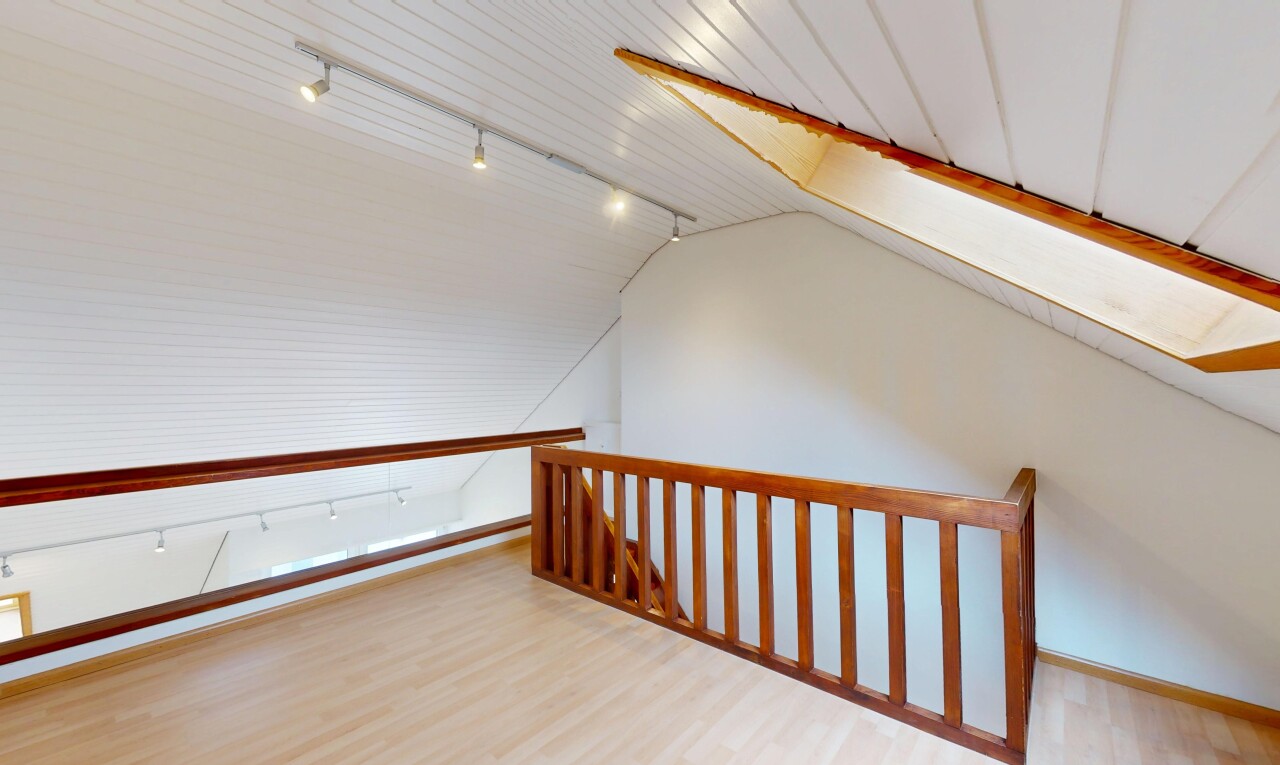 espace intérieur avec sol en finition bois, éclairage sur rail, plafond voûté, cloison sèche, et plinthes murales