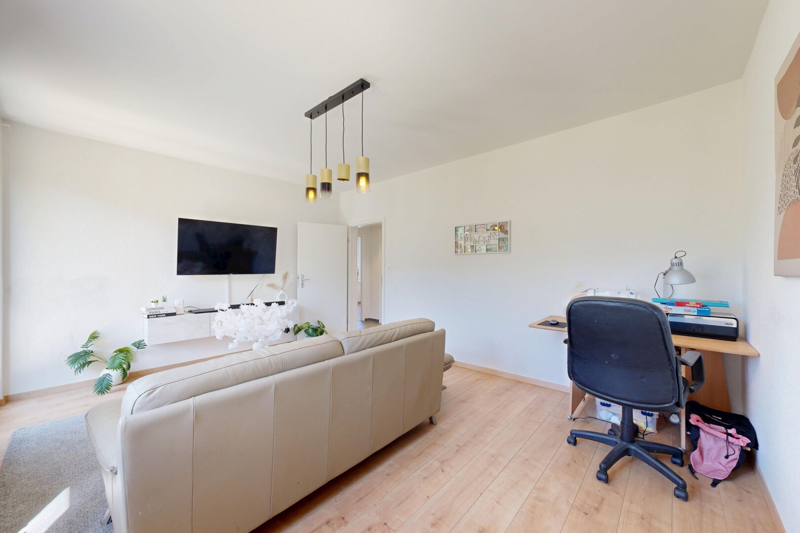 salon avec espace bureau, sol en finition bois, wood finish floor, télévision, et cloison sèche